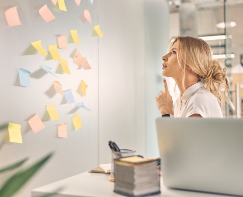 charming female worker sitting front wall with sticky notes pondering best solution office