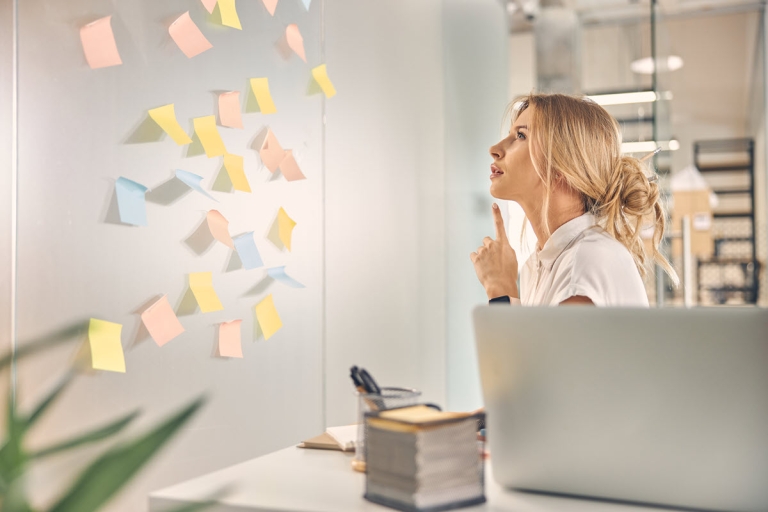charming female worker sitting front wall with sticky notes pondering best solution office