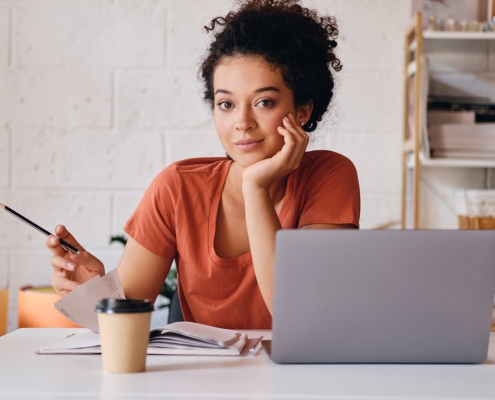 Platforma e-learningowa Spoti umożliwia tworzenie szkoleń zgodnych z wymaganiami IDD 3 mloda piekna studentka z ciemnymi kreconymi wlosami siedzi przy stole z laptopem i filizanka kawy aby isc opierajac sie na dloni marzycielsko patrzac w kamere olowkiem podczas nauki w przytu